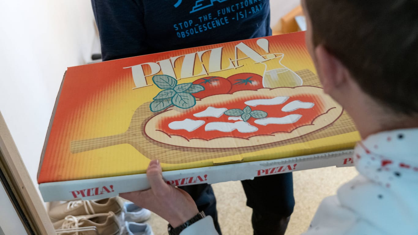 Ein Lieferant bringt einem Kunden eine Pizza nach Hause (Symbolbild): Die Kriminalpolizei ermittelt wegen versuchter räuberischer Erpressung.