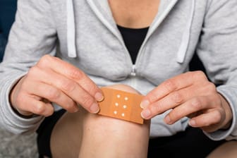 Eine Frau klebt sich ein Pflaster aufs Knie: Heilt eine Wunde, ist Juckreiz nicht ungewöhnlich.