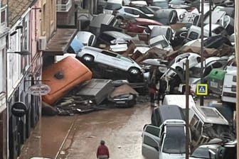 Autos türmen sich durch Wassermassen auf einem Haufen.