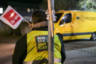 Ein Streikender trägt eine Weste mit der Aufschrift "Mehr Geld – Mehr Wert": Mitarbeiter von Geldtransporten wollen erneut streiken.