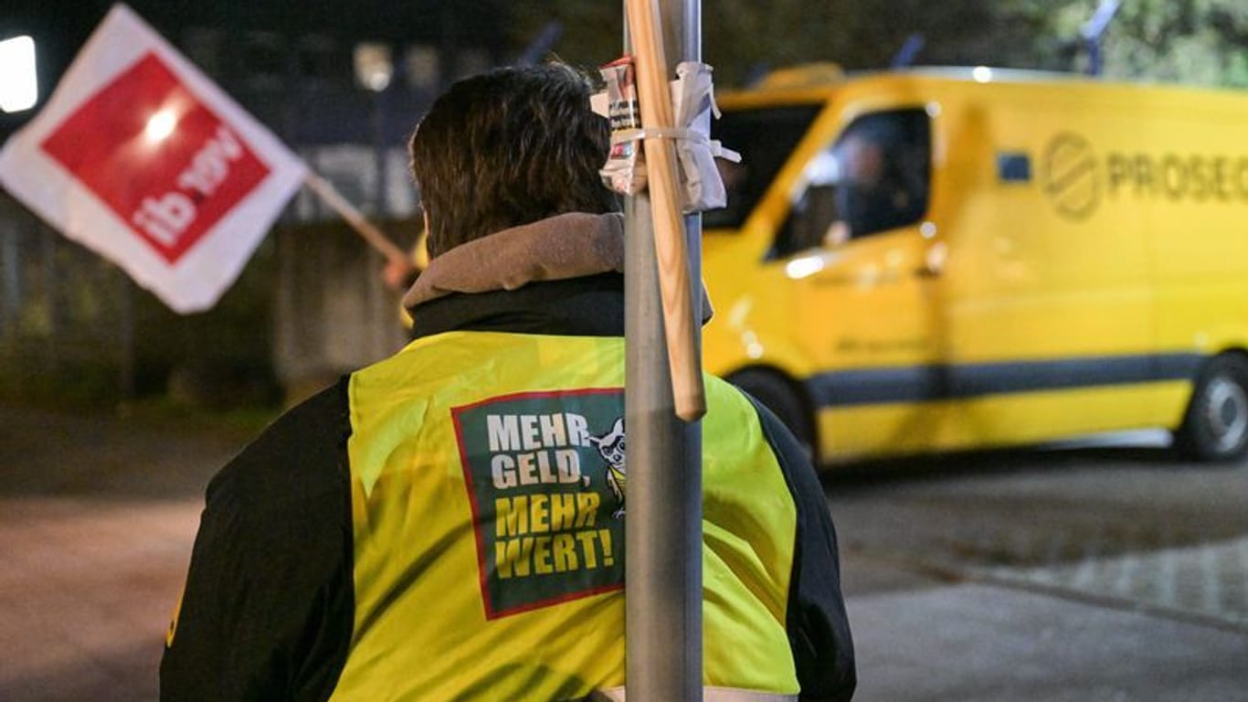 Ein Streikender trägt eine Weste mit der Aufschrift "Mehr Geld – Mehr Wert": Mitarbeiter von Geldtransporten wollen erneut streiken.