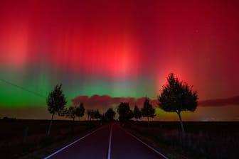 Polarlichter leuchten am Nachthimmel über einer Straße im östlichen Brandenburg.