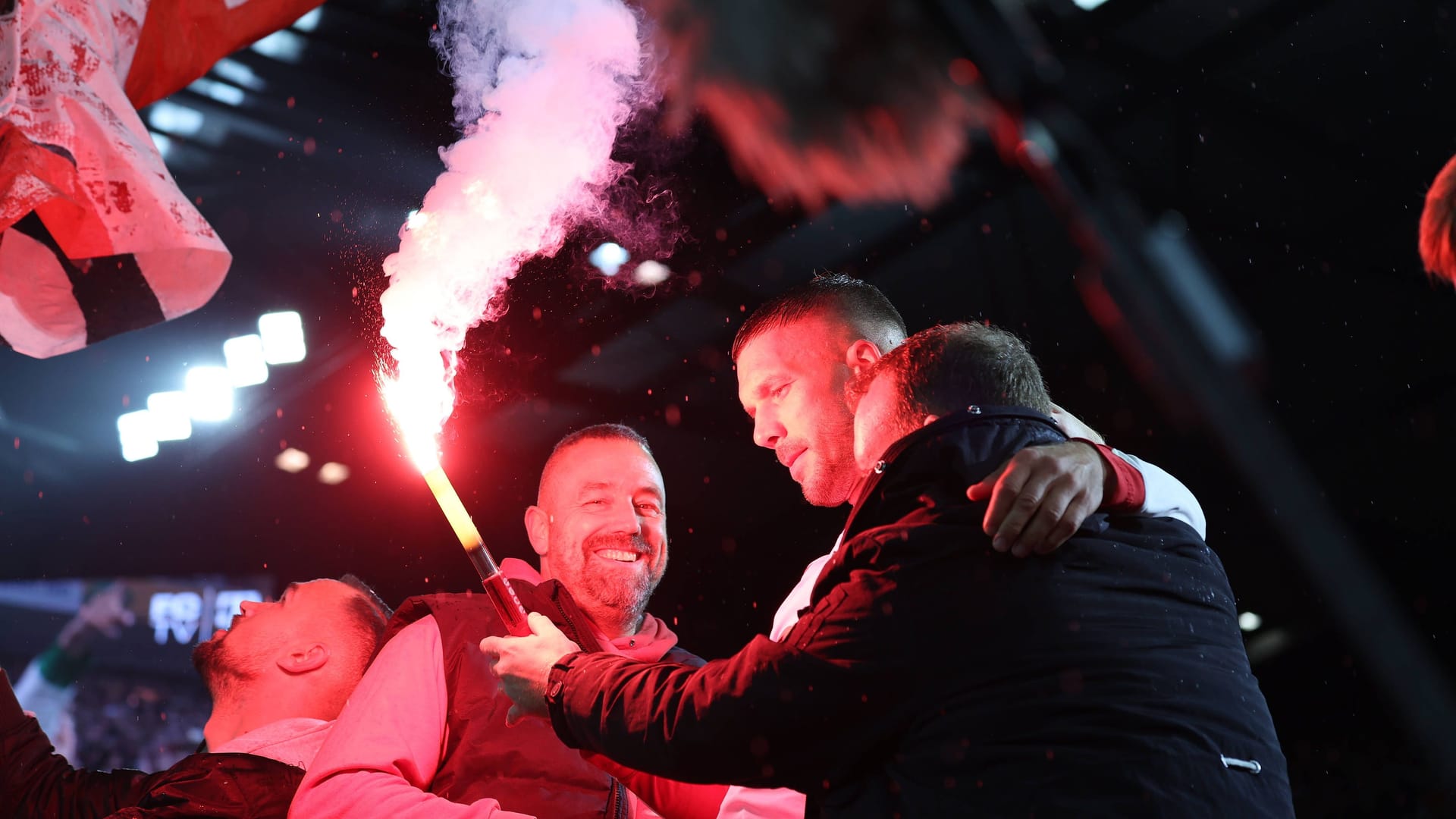 Lukas Podolski (Mitte) zwischen den Kölner Fans mit einer Pyrofackel.