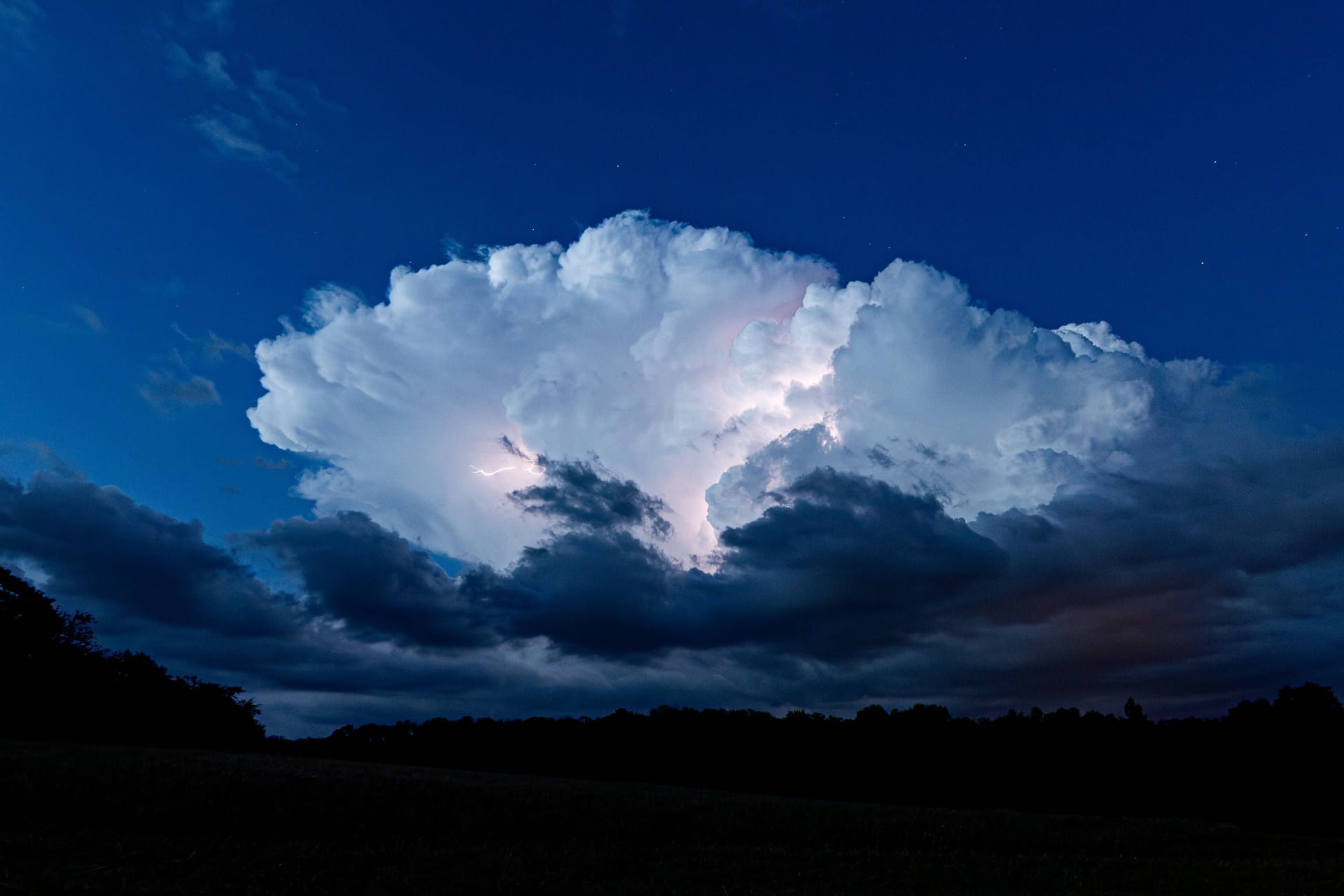 Ein Unwetter zieht mit Blitzen und Starkregen über den Himmel (Archivbild): Der Deutsche Wetterdienst hat für Ex-Hurrikan-Kirk die zweithöchste Warnstufe für Köln und Region herausgegeben.