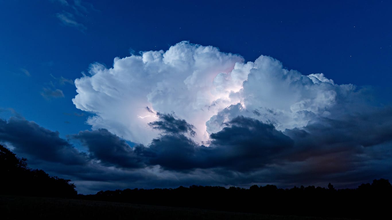 Ein Unwetter zieht mit Blitzen und Starkregen über den Himmel (Archivbild): Der Deutsche Wetterdienst hat für Ex-Hurrikan-Kirk die zweithöchste Warnstufe für Köln und Region herausgegeben.