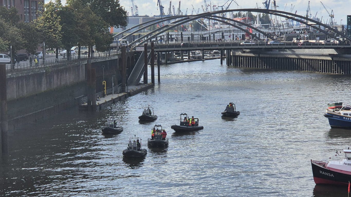 Feuerwehr und Polizei schwimmen auf Boten durch die Fleete.