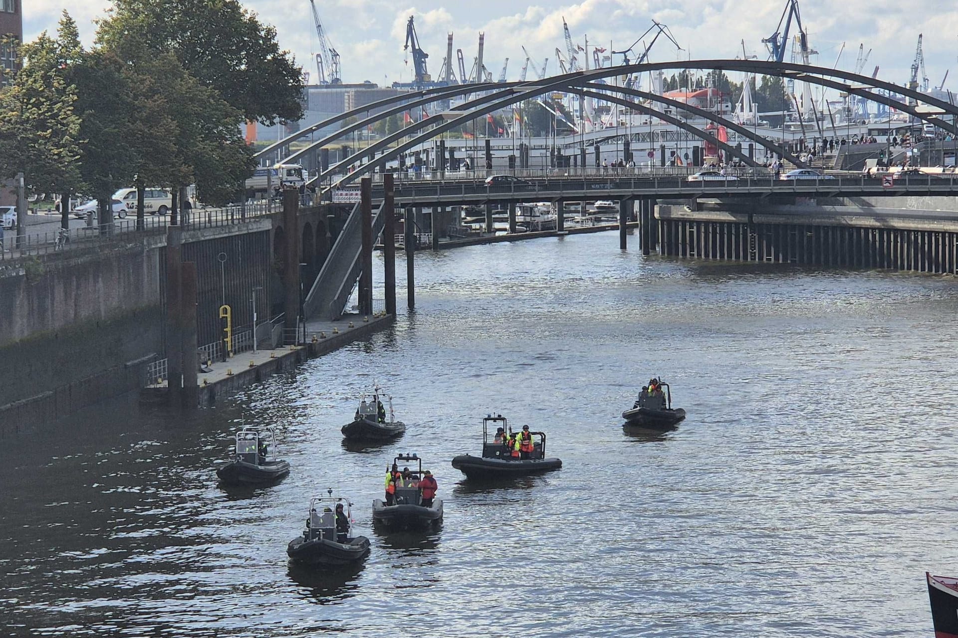 Feuerwehr und Polizei schwimmen auf Boten durch die Fleete.