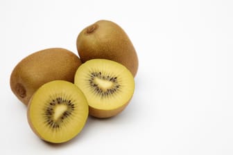 Whole and cut ripe yellow kiwis on white background