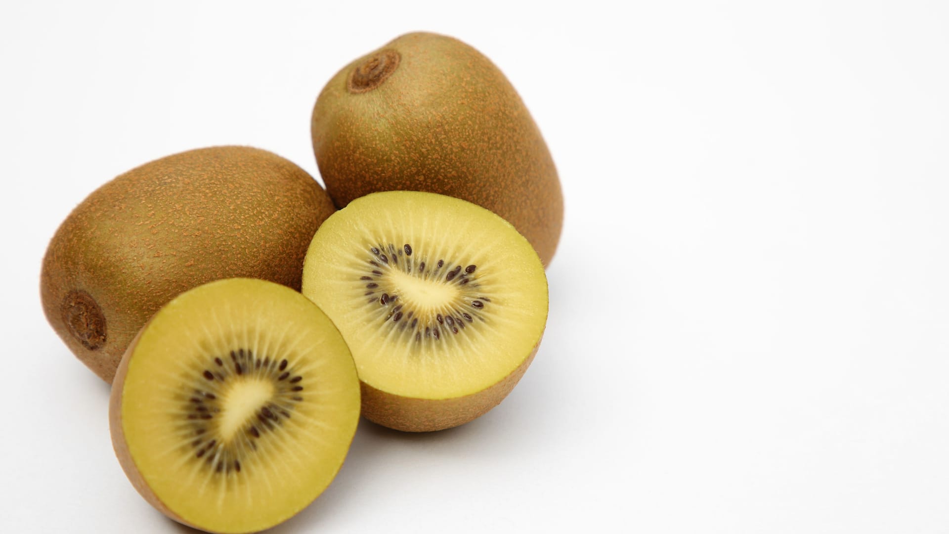 Whole and cut ripe yellow kiwis on white background