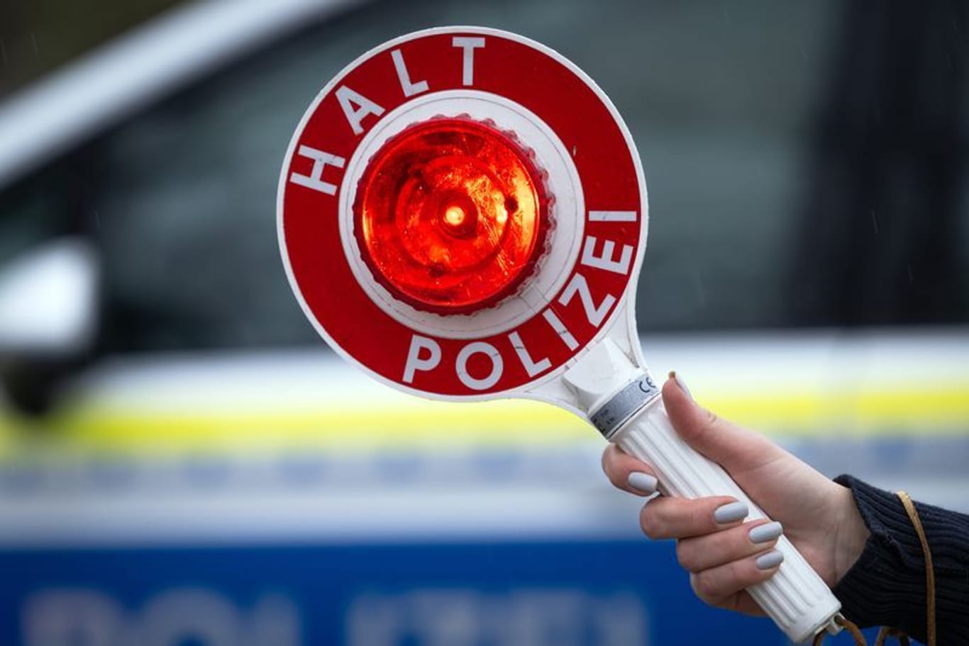 ARCHIV - 22.03.2024, Brandenburg, Trebbin: Eine Polizistin hält während einer Verkehrskontrolle an der Berliner Straße eine Polizeikelle mit der Aufschrift "Halt Polizei".