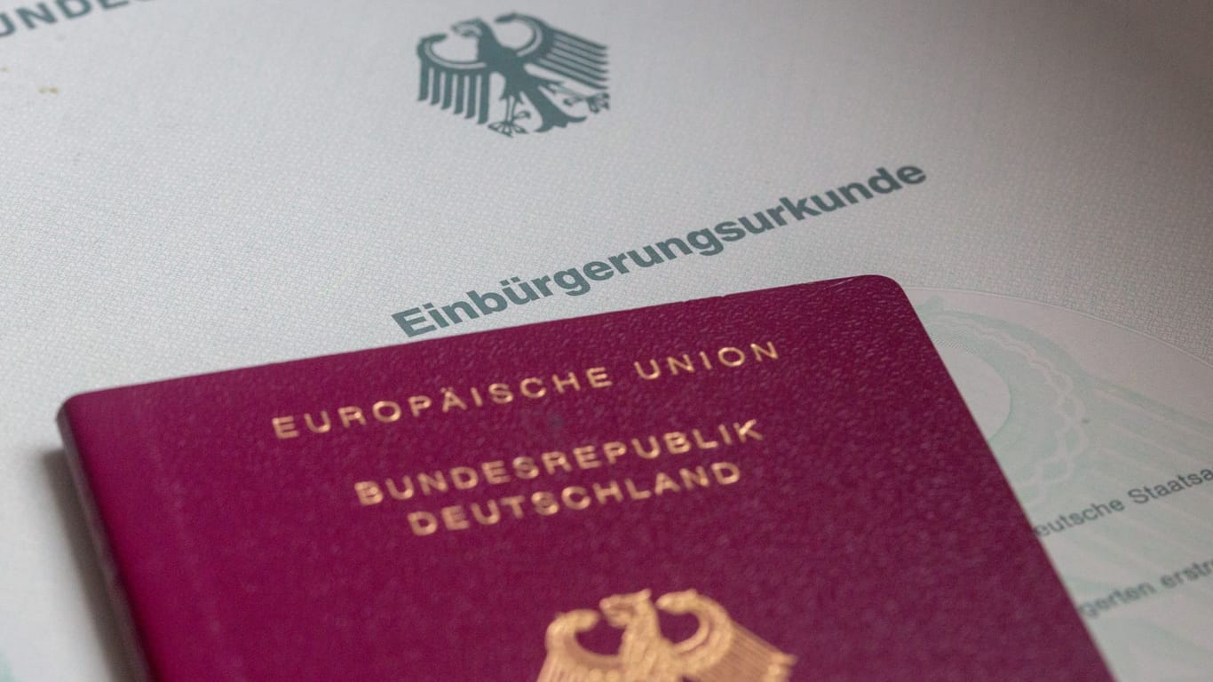 SYMBOLBILD - 02.02.2024, Berlin: Eine Einbürgerungsurkunde der Bundesrepublik Deutschland und ein deutscher Reisepass liegen auf einem Tisch.