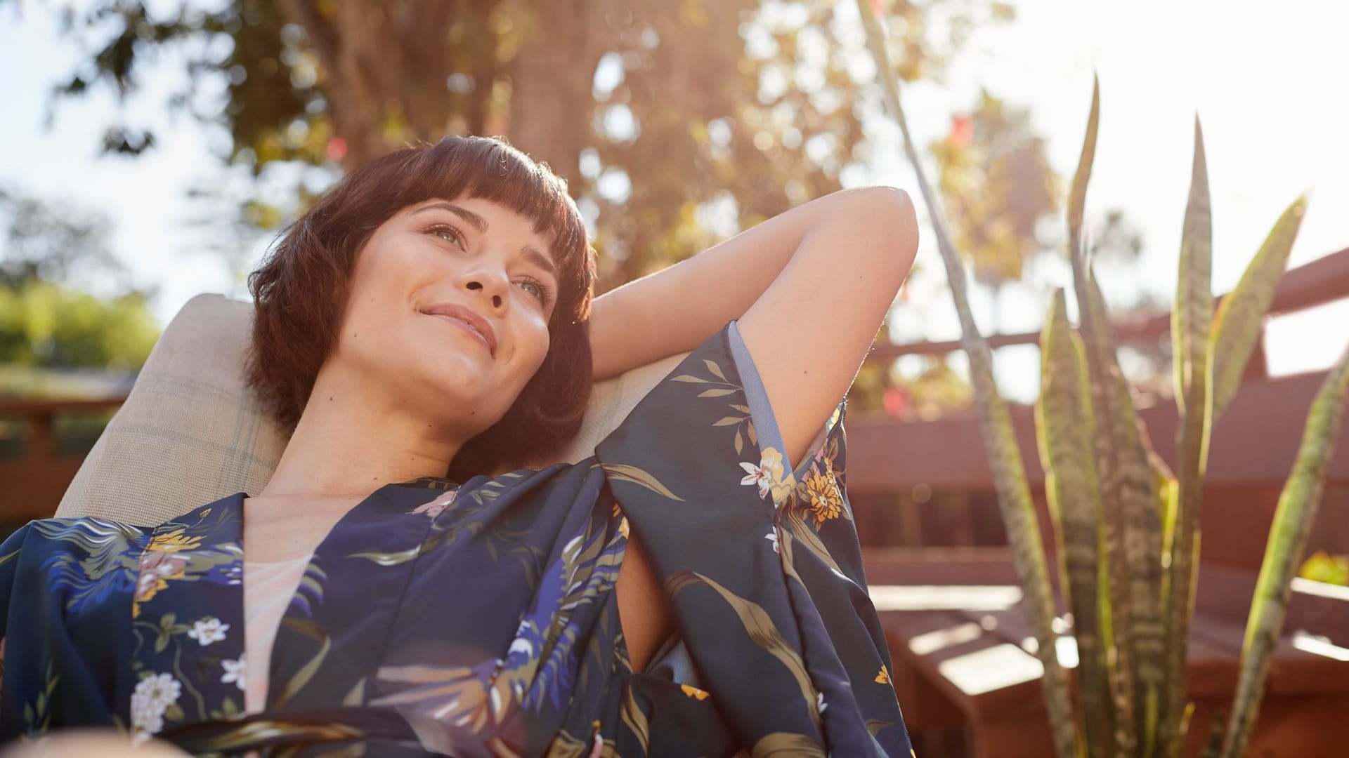 Frau sitzt im Garten und genießt die Sonne