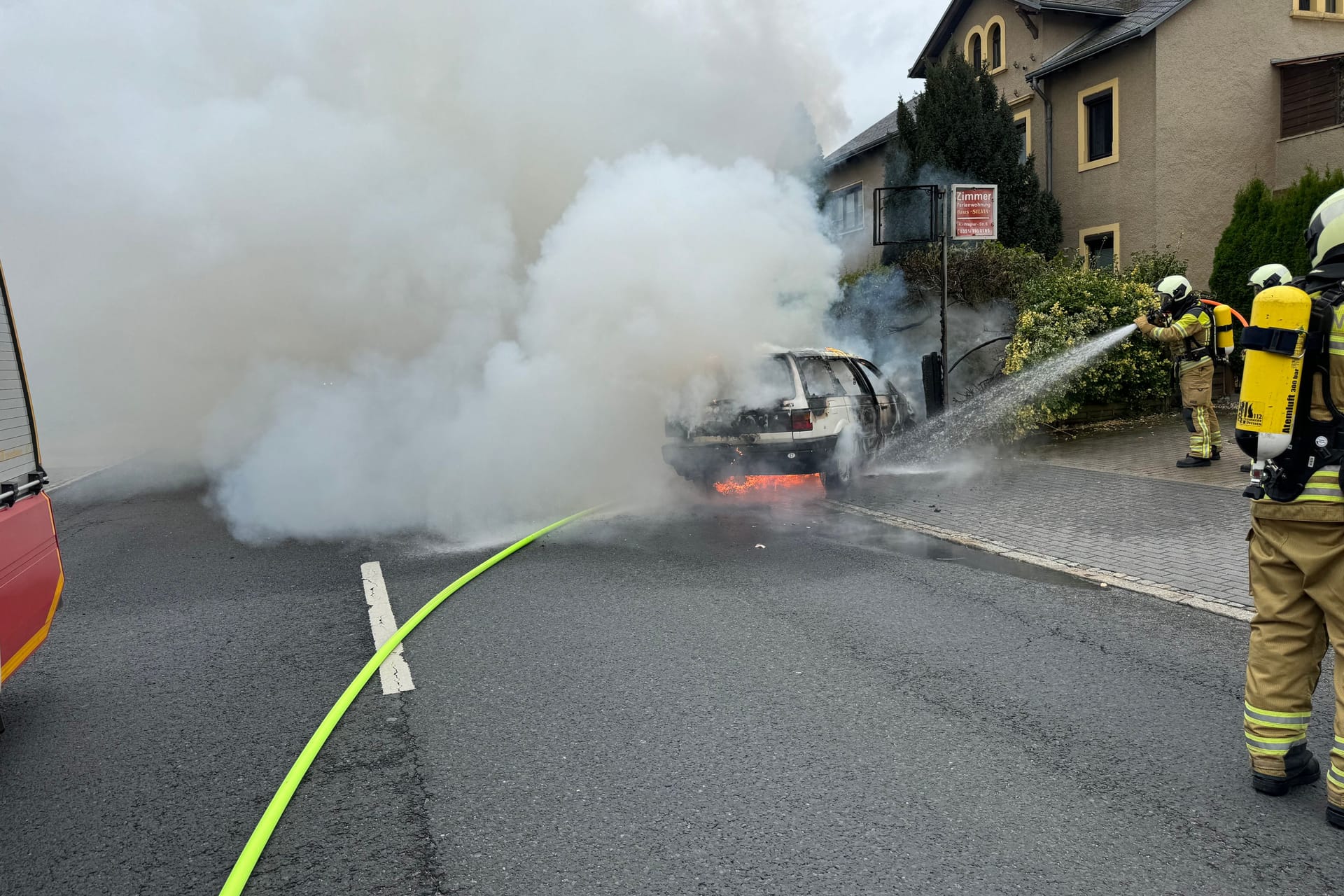 Einsatzkräfte unter Atemschutz nehmen die Brandbekämpfung auf: Das Fahrzeug geriet in Flammen.