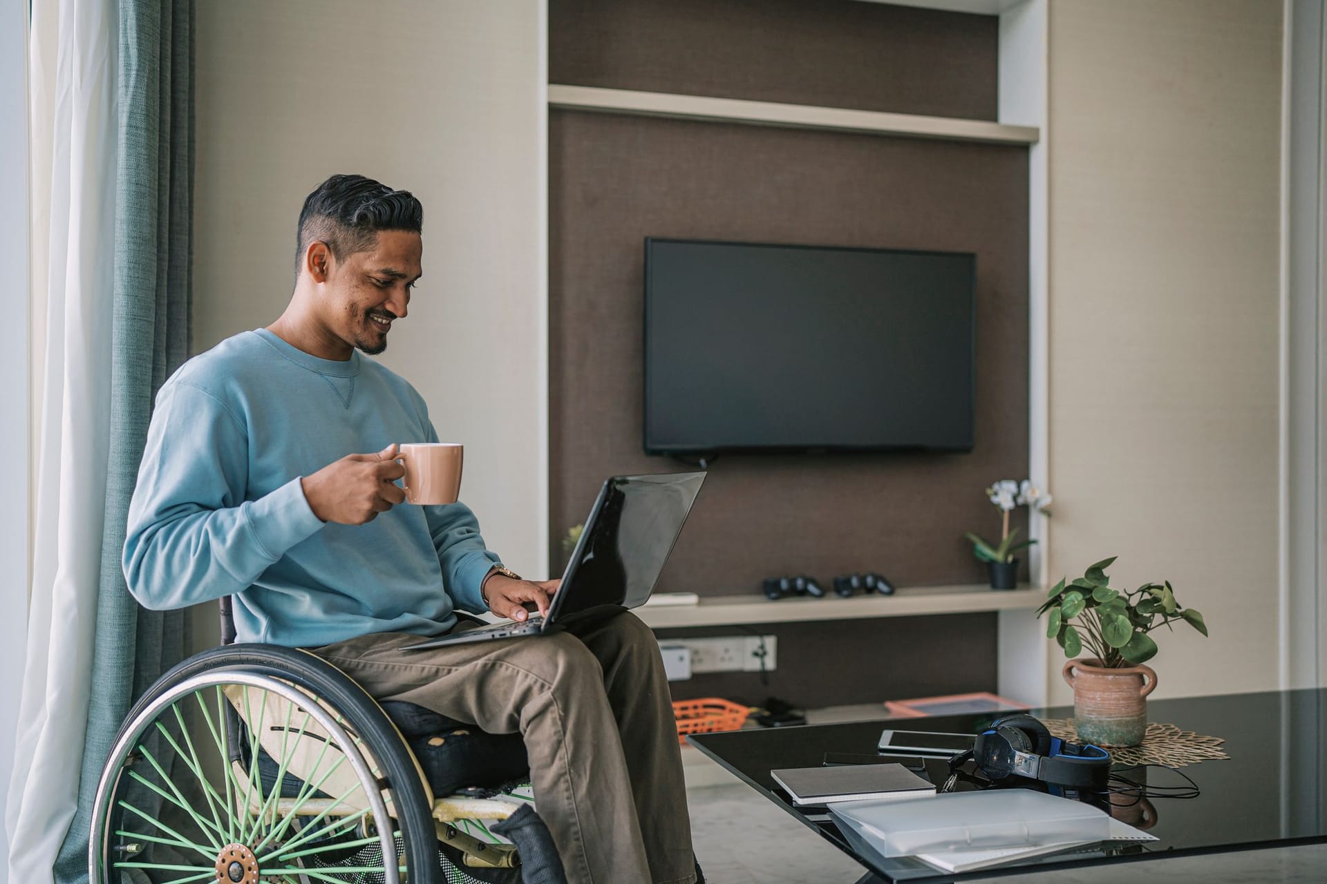 Mann sitzt im Rollstuhl und arbeitet auf seinem Laptop