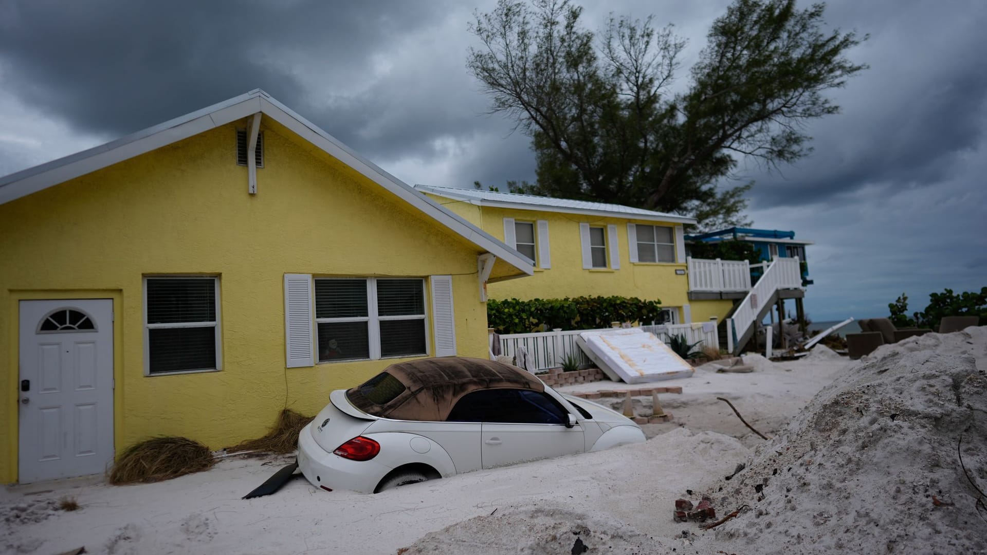 Ein Auto liegt nach Hurrikan "Helene" halb vergraben im Sand in Bradenton Beach: Bald wird hier der nächste Sturm erwartet.