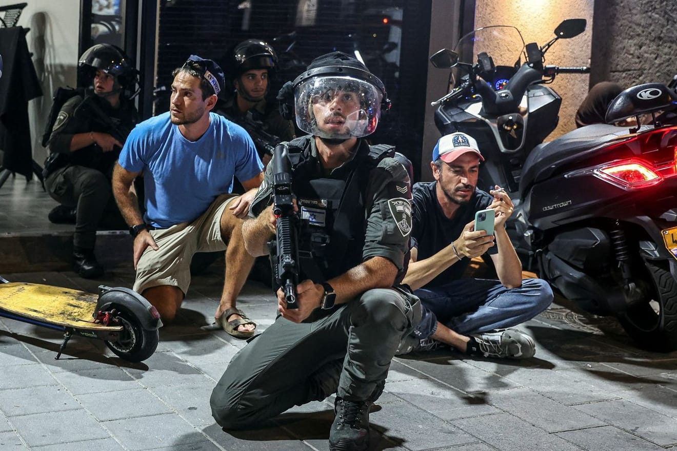 Tel Aviv: Israelische Polizisten und Soldaten gehen nach dem Luftalarm wegen der iranischen Raketen in Deckung.