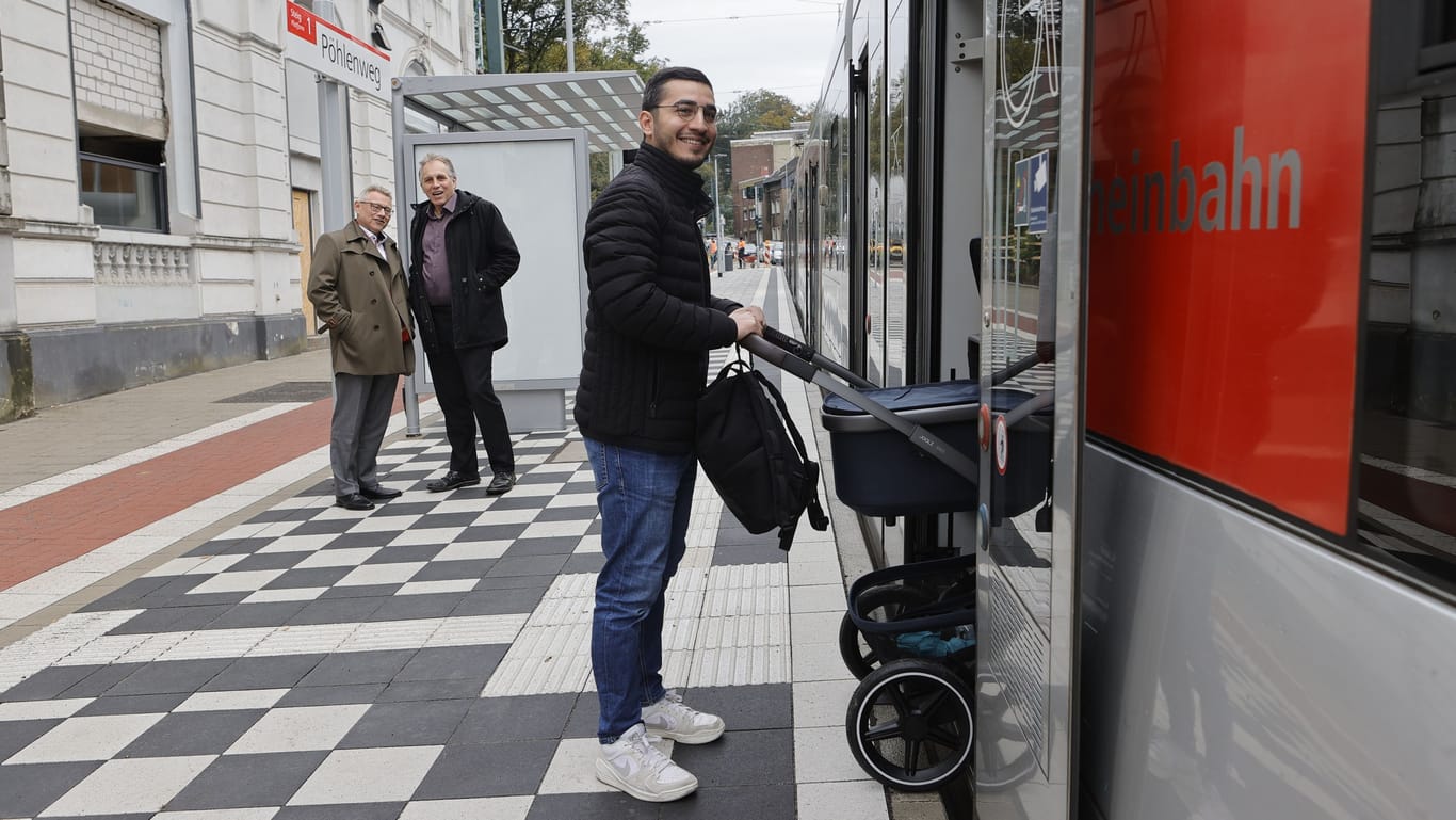 Hamit Özdemir, Projektingenieur der Rheinbahn, testet die Haltestelle „Pöhlenweg“ mit dem Kinderwagen. Im Hintergrund Rheinbahn-Vorstand Michael Richarz und Mobilitätsdezernent Jochen Krahl.