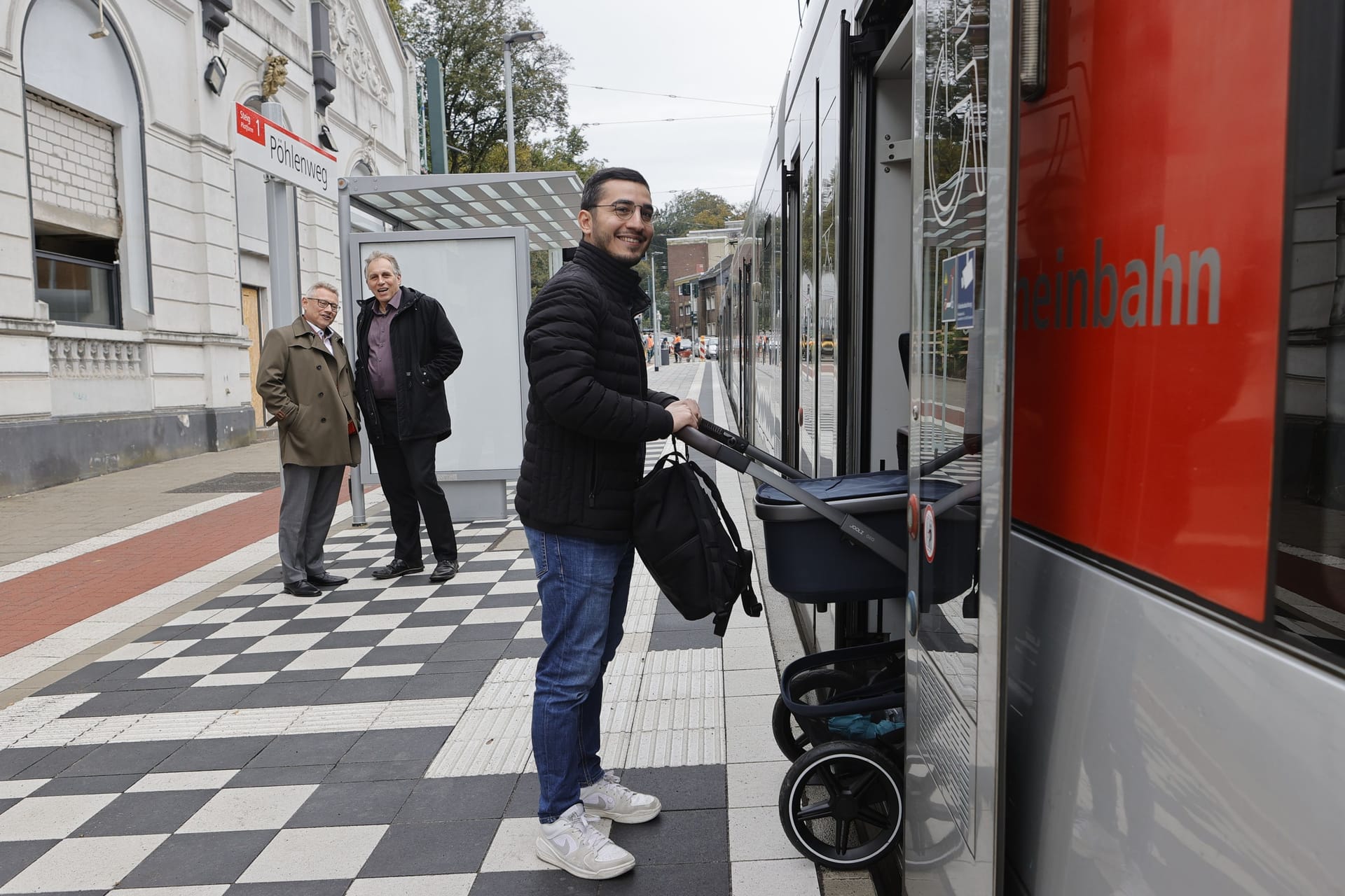 Hamit Özdemir, Projektingenieur der Rheinbahn, testet die Haltestelle „Pöhlenweg“ mit dem Kinderwagen. Im Hintergrund Rheinbahn-Vorstand Michael Richarz und Mobilitätsdezernent Jochen Krahl.