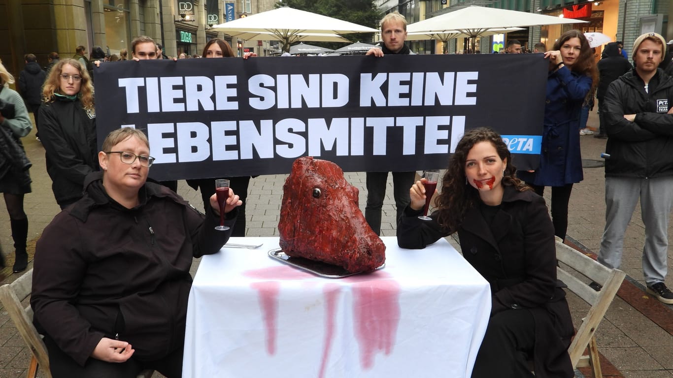 Demonstranten sitzen an einem Tisch mit einem unechten Kuhkopf darauf: Die Aktion von Peta in der Spitalerstraße sollte Aufmerksamkeit erregen.