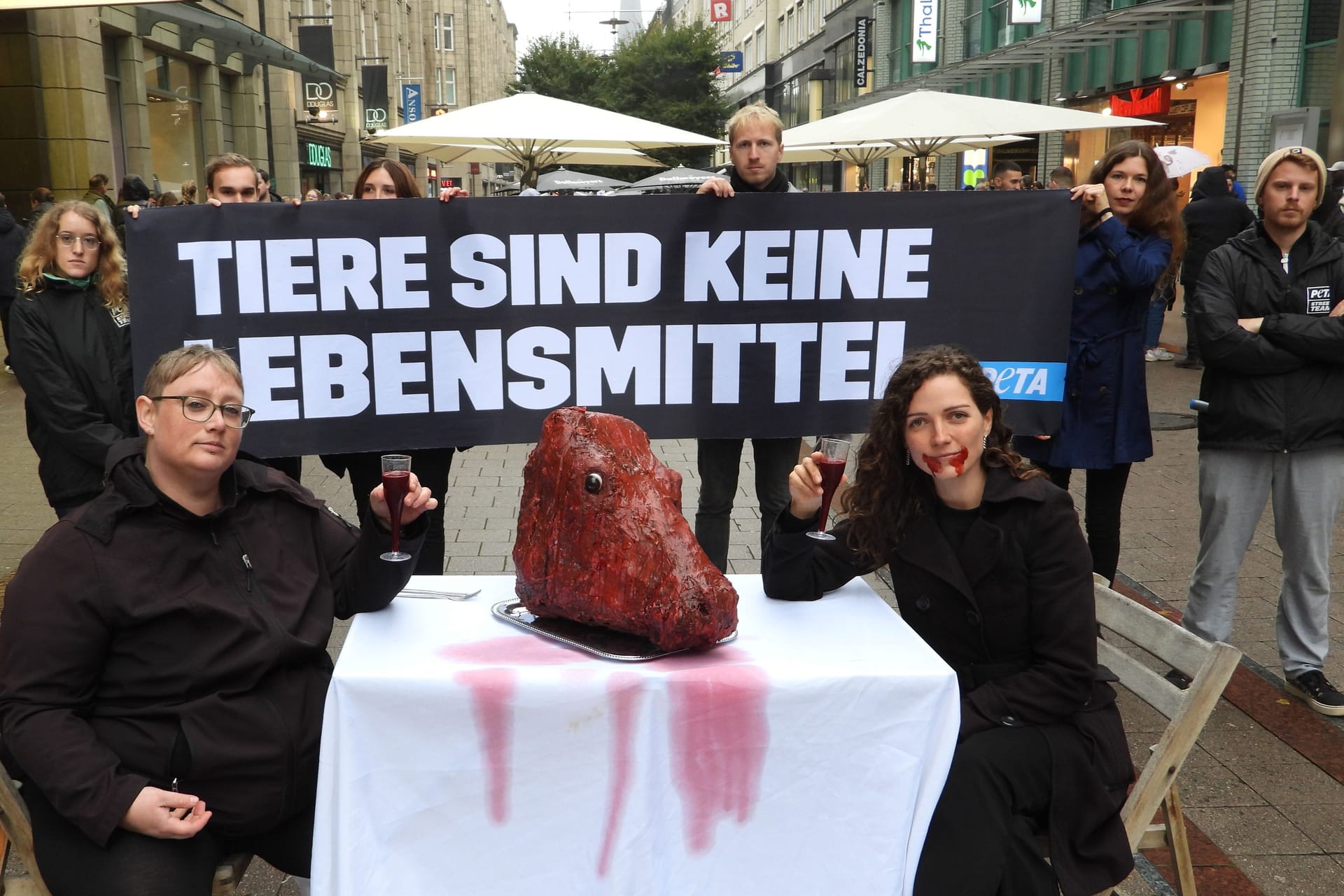 Demonstranten sitzen an einem Tisch mit einem unechten Kuhkopf darauf: Die Aktion von Peta in der Spitalerstraße sollte Aufmerksamkeit erregen.