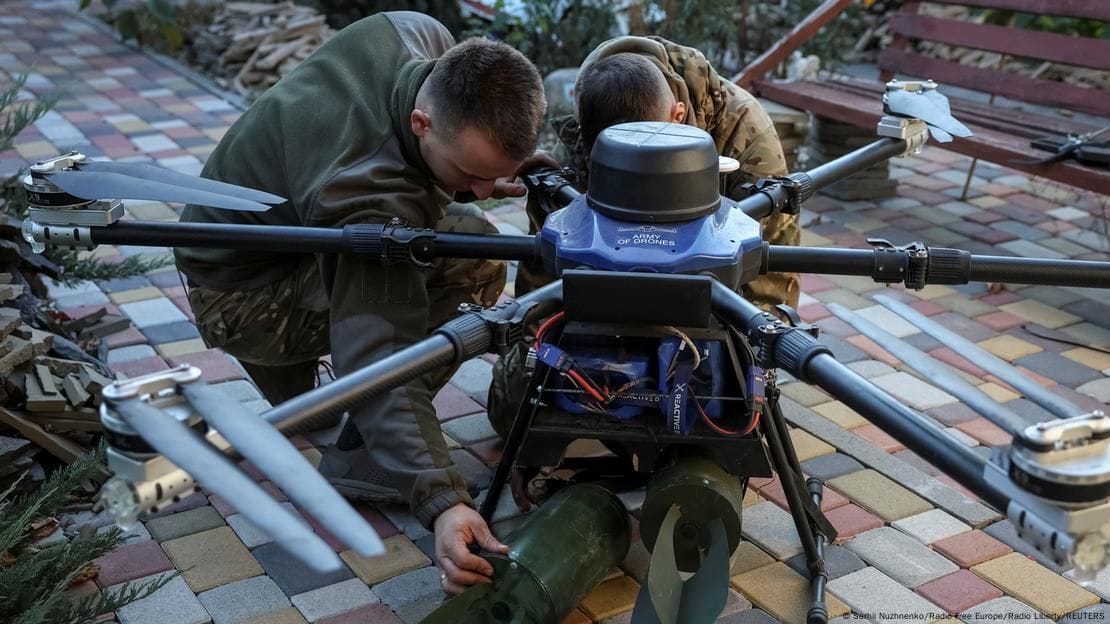 Ukrainische Soldaten befestigen Sprengsätze an einer Kampfdrohne.