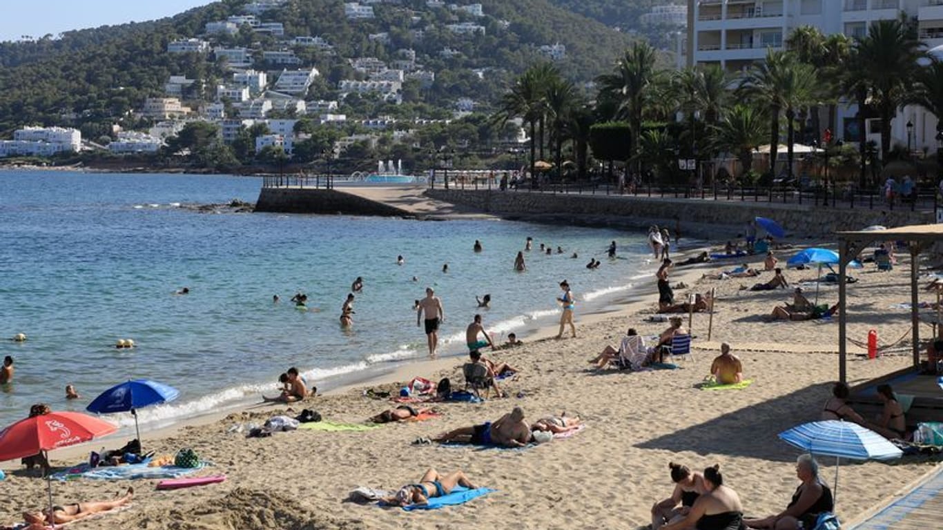 Menschen sonnen sich am Strand von Santa Eulalia auf Ibiza.