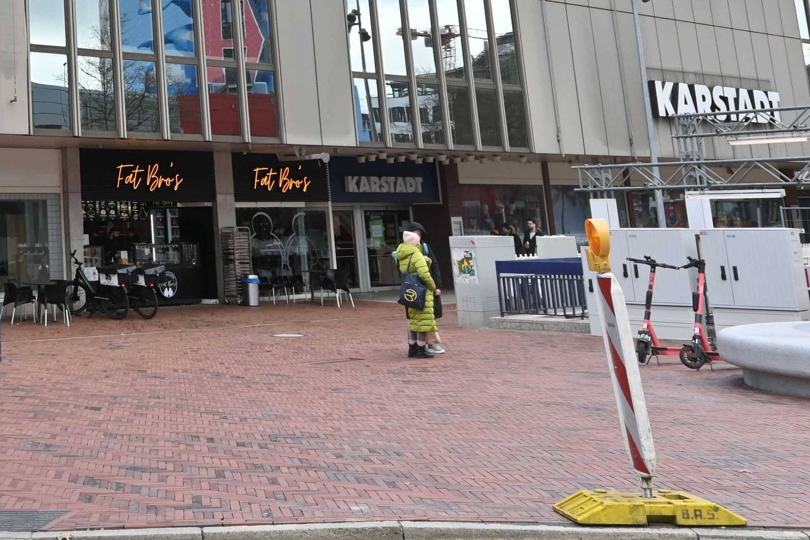 Das frühere Karstadt-Haus in Hamburg-Harburg (Archivbild). Das Bild zeigt das Gebäude von außen. Im Vordergrund ist eine S-Bahnstation sichtbar. Menschen gehen vor dem Kaufhaus vorbei. Der Himmel ist blau und bewölkt.