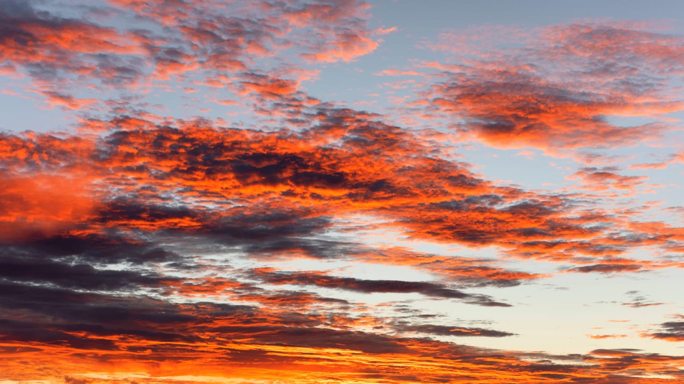 Mehrere Wolken vor einem Sonnenuntergang (Archivbild): Die ersten Wetterprognosen zum 11.11. in Köln lassen auf außergewöhnlich hohe Temperaturen schließen.