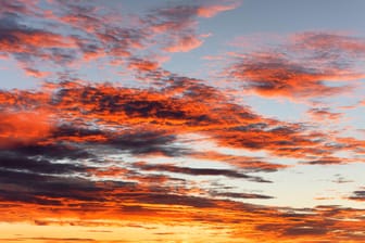 Mehrere Wolken vor einem Sonnenuntergang (Archivbild): Die ersten Wetterprognosen zum 11.11. in Köln lassen auf außergewöhnlich hohe Temperaturen schließen.