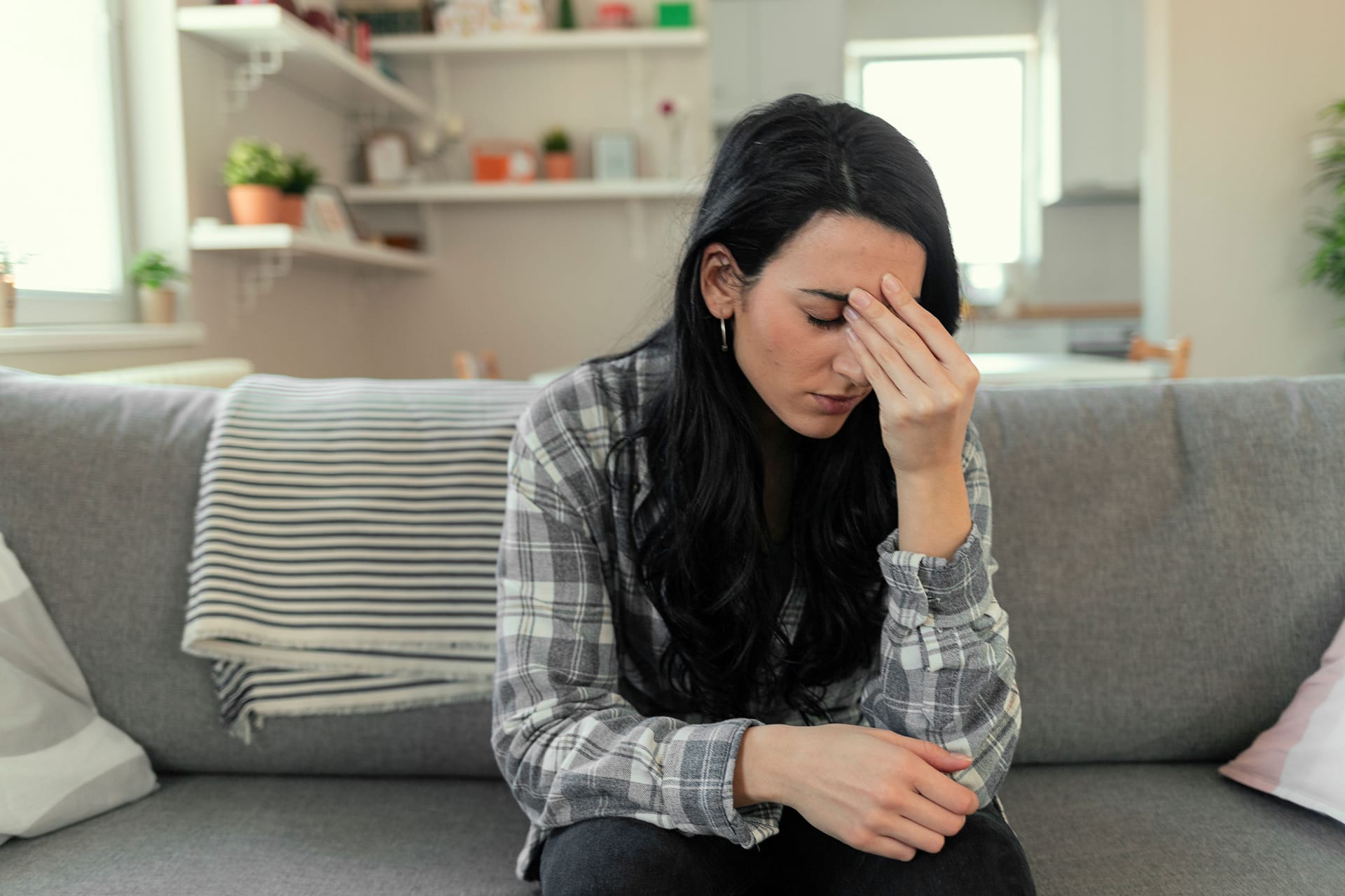 Junge Frau sitzt auf dem Sofa und fühlt sich nicht wohl