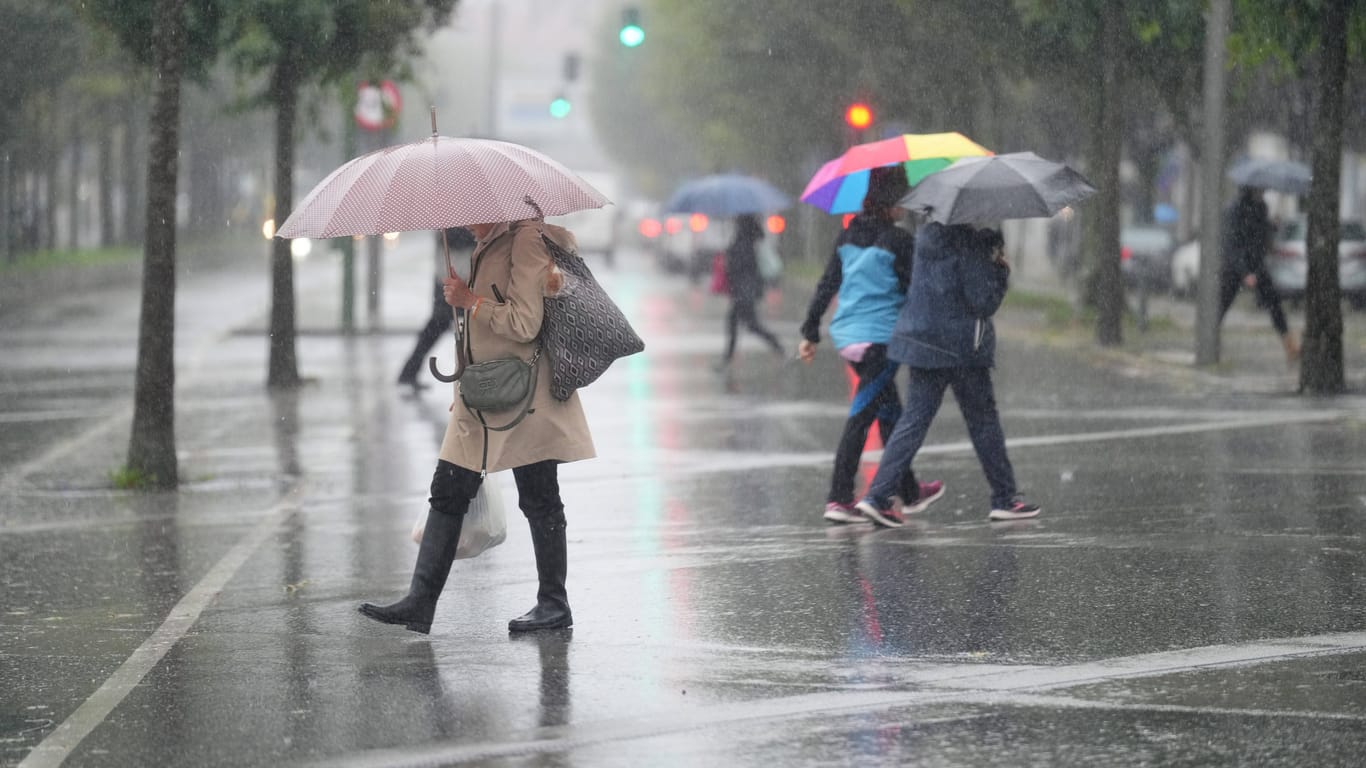 Passanten laufen durch den Regen. (Symbolbild) Am Mittwoch kommt es in der Region zu Starkregen und Sturmböen.