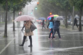 Passanten laufen durch den Regen. (Symbolbild) Am Mittwoch kommt es in der Region zu Starkregen und Sturmböen.