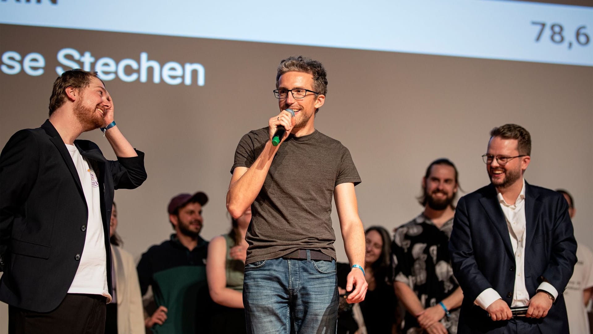 Vorjahressieger René Greschert (Mitte) neben den Moderatoren der Landesmeisterschaft im Poetry Slam 2023 in Krefeld, Johannes Floehr (Links) und Bernard Hoffmeister (Rechts)