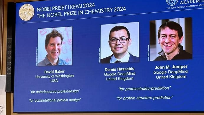 Drei Forscher teilen sich den Preis: Auf der Leinwand während der Pressekonferenz zur Bekanntgabe des Chemie-Nobelpreises 2024 werden Bilder von David Baker, Demis Hassabis, und John M. Jumper gezeigt.