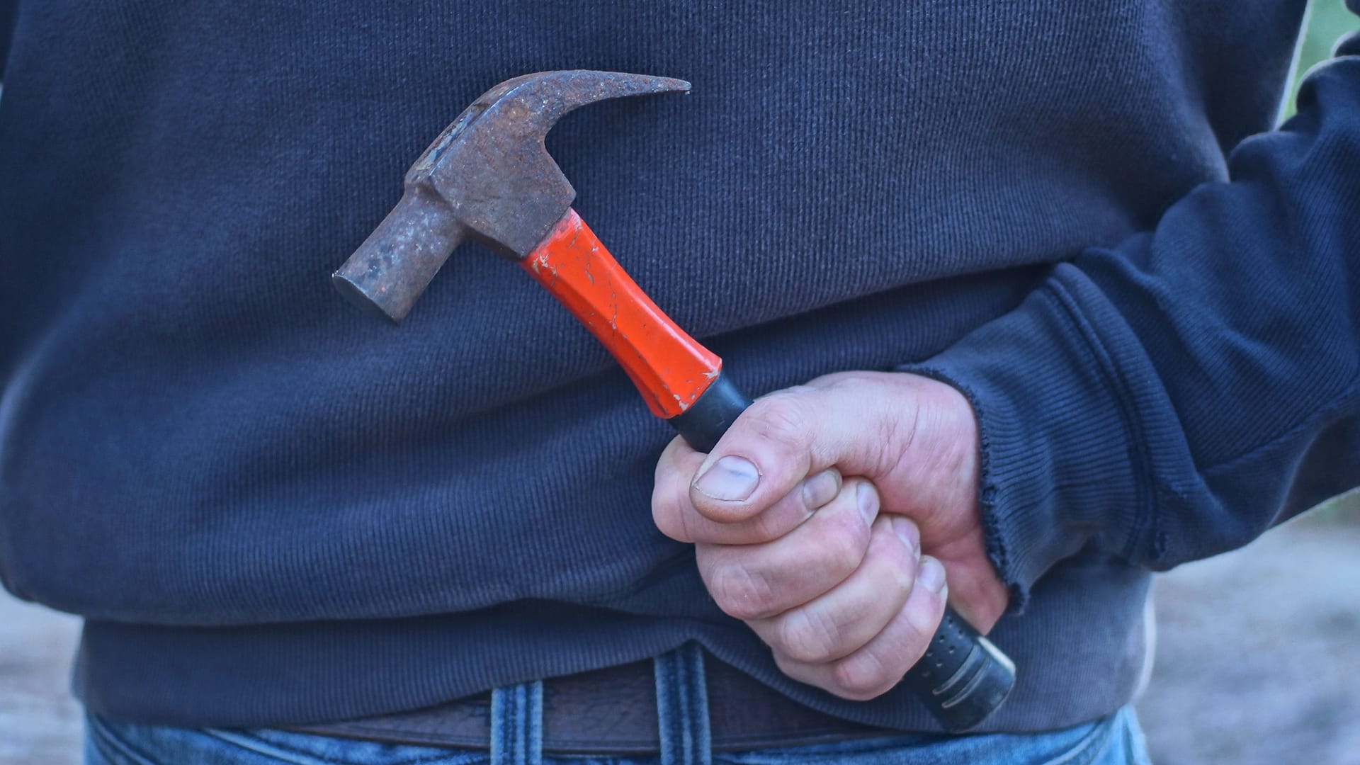 Mann mit Hammer hinter dem Rücken (Symbolbild): Eine der beiden Schülerinnen konnte Hilfe alarmieren.