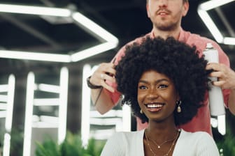 Young african woman customer getting a hairstyle at a beauty salon.