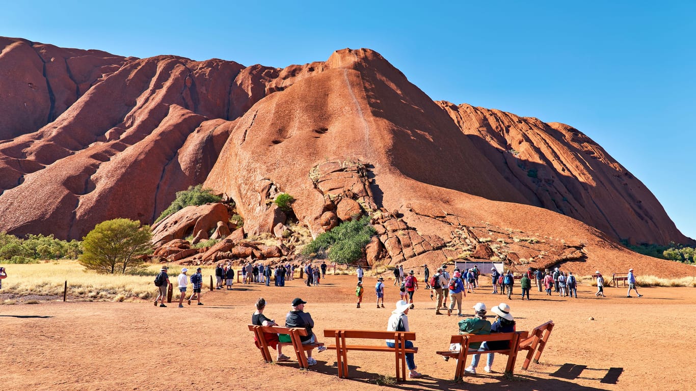 Touristen am Fuß des Uluru: Von unten kann er auch heute noch bestaunt werden.