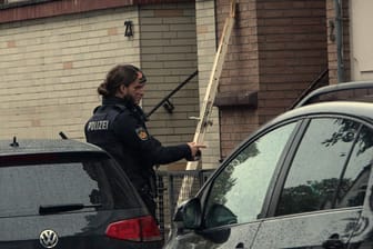 Polizisten an der mutmaßlich durch eine Explosion herausgerissene Tür. Bislang äußern sich die Beamten nicht zu den Hintergründen des Vorfalls.