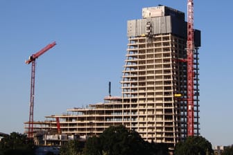 Der in ein Gerüst gehüllte Rohbau des Elbtowers in der Hamburger Hafencity. Drumherum stehen Kräne. Der Himmel ist blau, es ist sonnig.