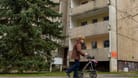 Eine ältere Frau läuft mit ihrem Rollator in der Hand an einem alten Plattenbau im sächsischen Heidenau vorbei. Die ehemalige Industriestadt, hat noch zahlreiche solche DDR-Bauten im Stadtgebiet imago images 151738546