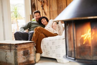 Paar sitzt zufrieden im Haus und wärmt sich am Kaminfeuer auf