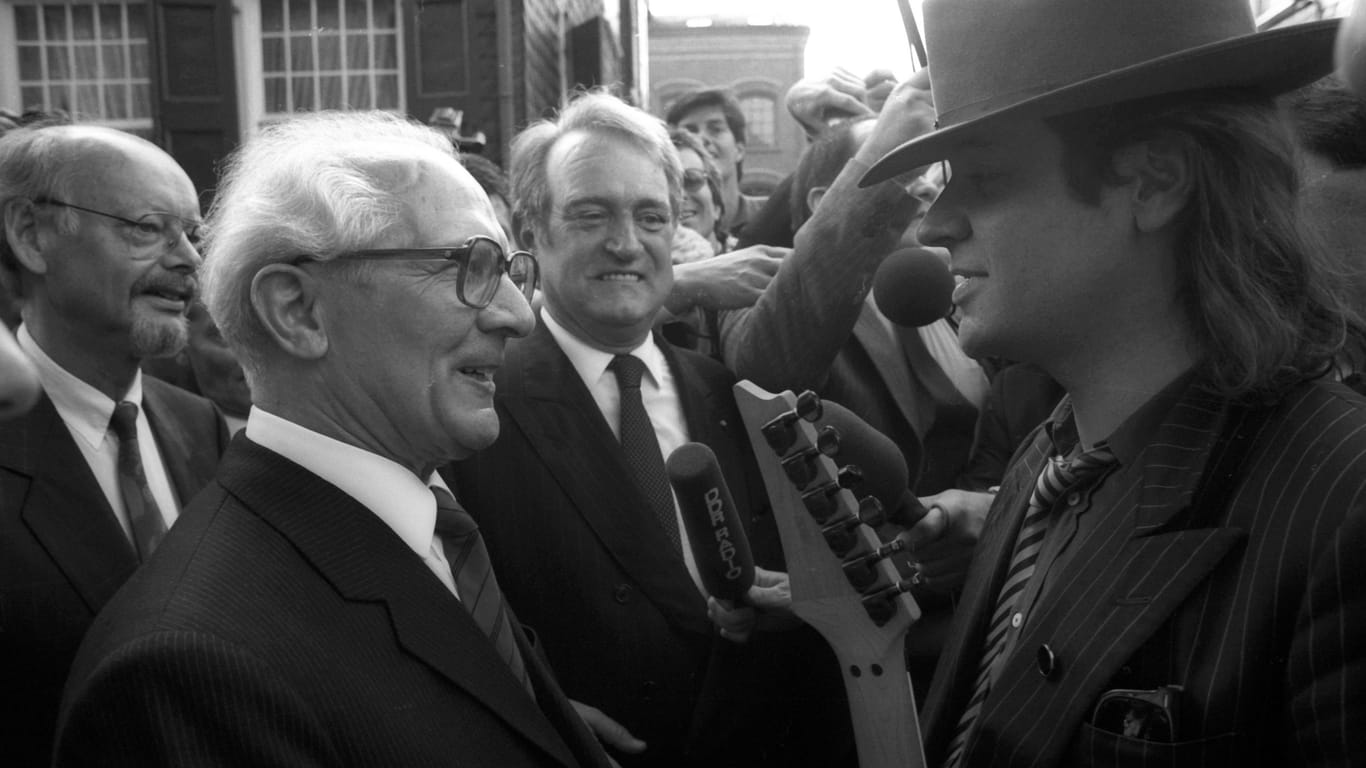 Sänger Udo Lindenberg re. überreicht Erich Honecker DDR/Staatsratsvorsitzender im Beisein von Johannes Rau Mitte, BRD/SPD/Ministerpräsident NRW eine Gitarre