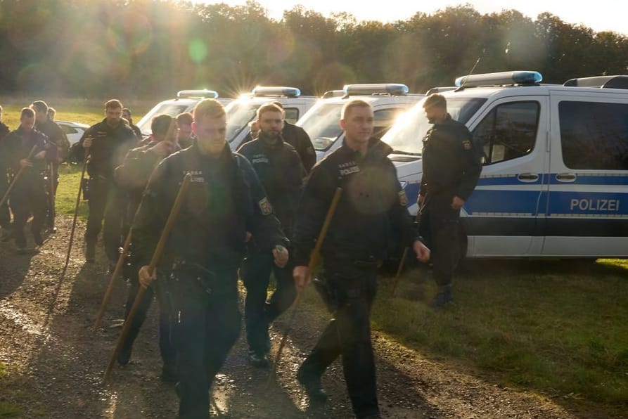 Polizisten suchen die Umgebung nach dem Fund von zwei Leichen ab.