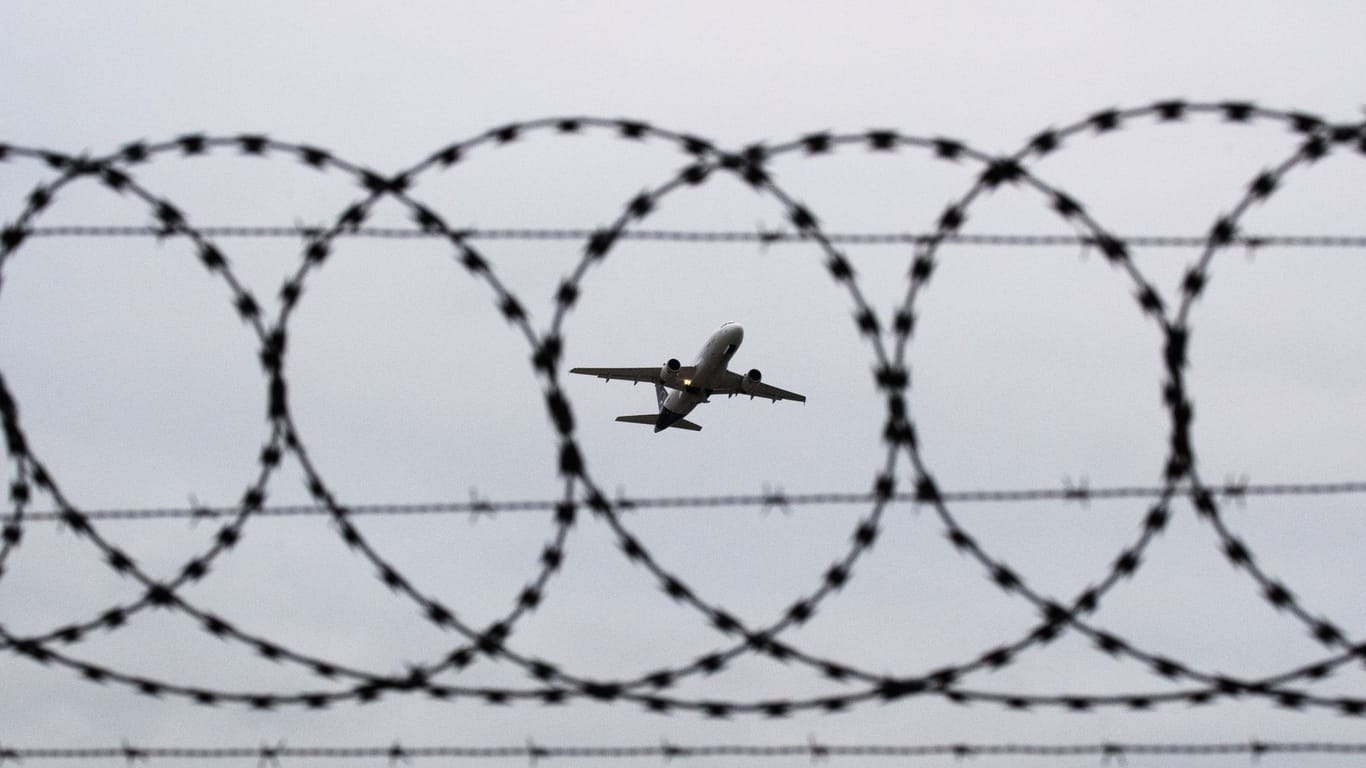 Flugzeug fotografiert durch Stacheldraht am Flughafenzaun (Symbolbild): In Hamburg igbt es eine Debatte um Abschiebung aus dem Kirchenasyl.