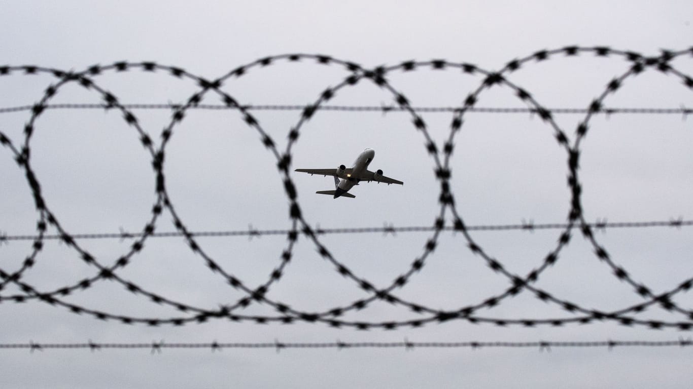 Flugzeug fotografiert durch Stacheldraht am Flughafenzaun (Symbolbild): In Hamburg igbt es eine Debatte um Abschiebung aus dem Kirchenasyl.