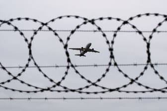 Flugzeug fotografiert durch Stacheldraht am Flughafenzaun (Symbolbild): In Hamburg igbt es eine Debatte um Abschiebung aus dem Kirchenasyl.