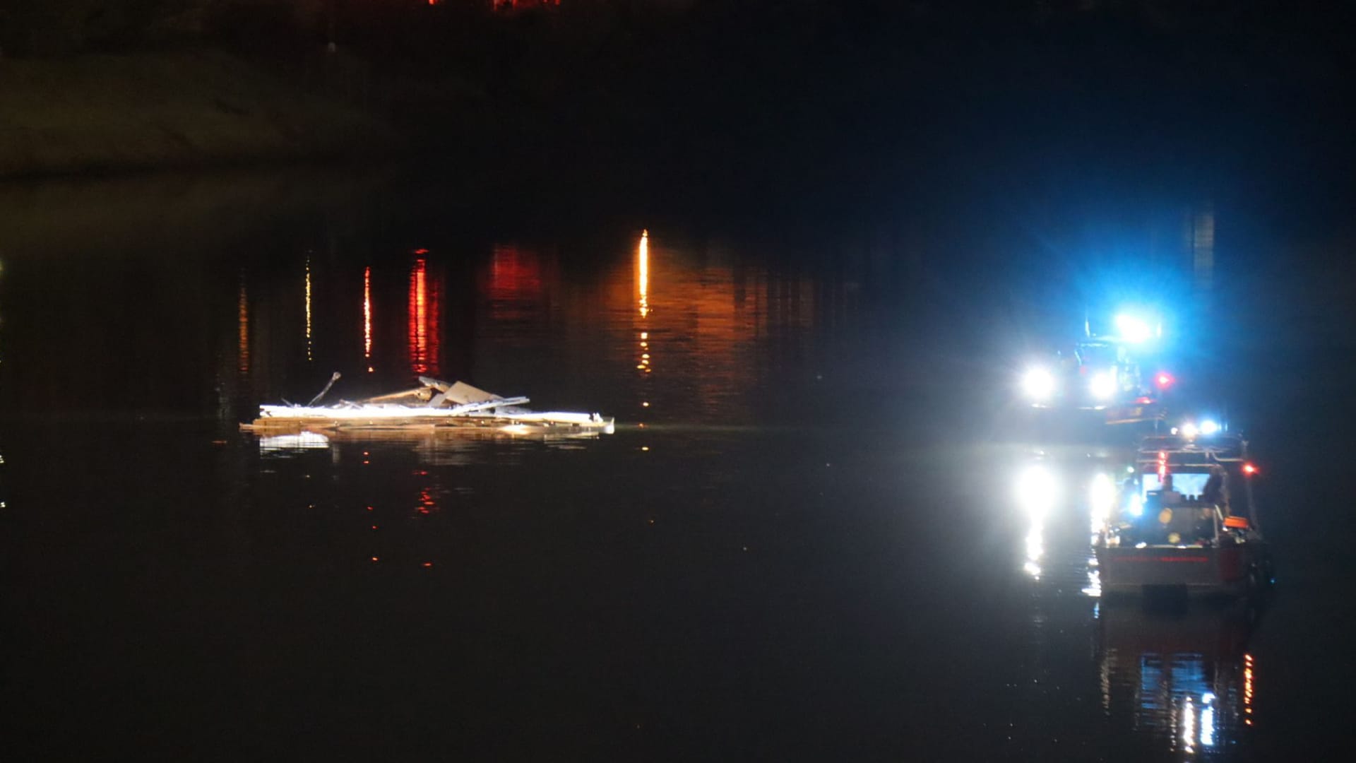 Teile eines Schiffes schwimmen im Wasser im Mannheimer Industriehafen, während Boote im Einsatz sind.