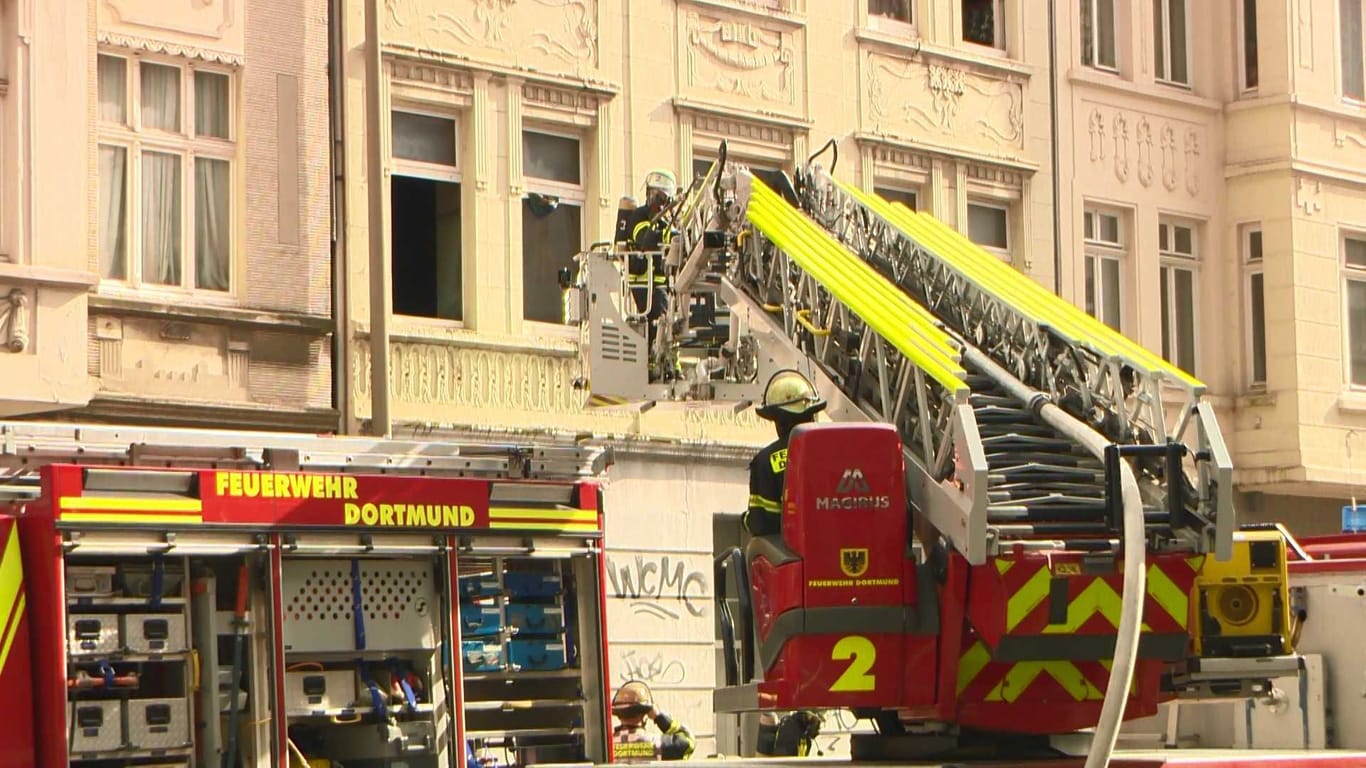 Am frühen Nachmittag des 04.10.2024 wurde der Leitstelle der Feuerwehr Dortmund ein Wohnungsbrand in einem Mehrfamilienhaus in der Bornstraße gemeldet. Umgehend wurden zwei Löschzüge der Berufsfeuerwehr, die zuständige Freiwillige Feuerwehr sowie der Rettungsdienst entsendet.Bei Eintreffen der ersten Kräfte schlugen auf der Gebäuderückseite des Mehrfamilienhauses bereits Flammen aus einem Balkonfenster im 1. Obergeschoss. Durch die hohe Brandintensität breitete sich der Brand auf die darüberliegenden Geschosse rasant aus. Außerdem drang Rauch in angrenzende Wohnungen des betroffenen Gebäudes sowie der beiden Nachbarhäuser ein.