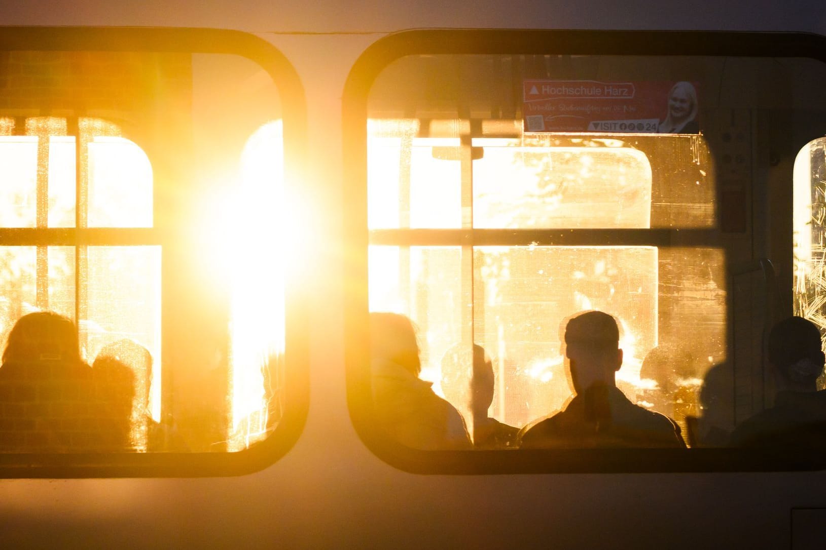 Fahrgäste sitzen bei Sonnenaufgang in einer Stadtbahn Fahrgäste sitzen bei Sonnenaufgang in einer Stadtbahn