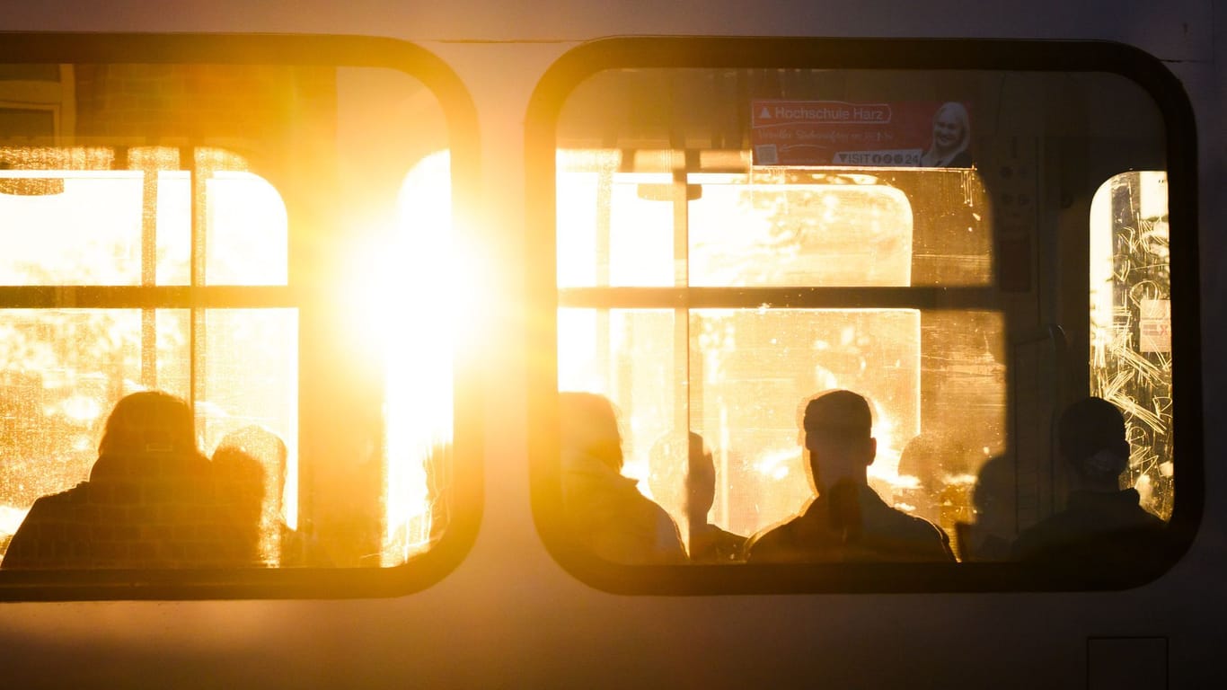 Fahrgäste sitzen bei Sonnenaufgang in einer Stadtbahn